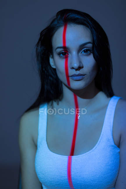 Молодая привлекательная женщина с красной линией на лице и теле смотрит в камеру — стоковое фото
