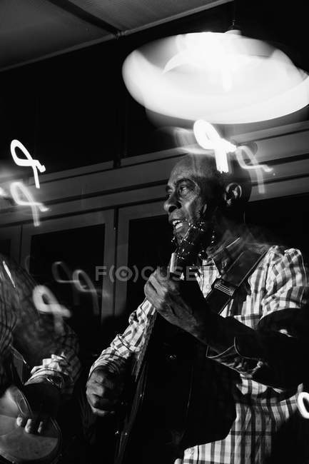 Músicos tocando guitarra e bateria em boate, tiro preto e branco com longa exposição — Fotografia de Stock