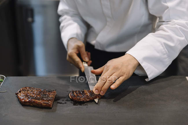 Koch schneidet gegrilltes Rindfleisch im Restaurant — Stockfoto