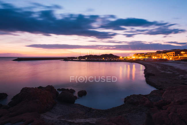 Ville éclairée et baie au coucher du soleil, Sardaigne, Italie — Photo de stock