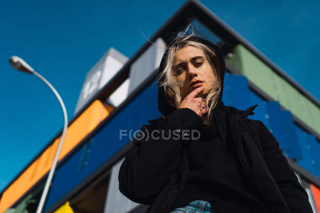 Attrayant blonde femme regardant caméra contre bâtiment coloré — Photo de stock
