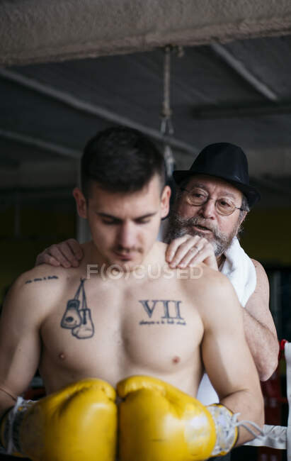 Adult trainer warming up neck of sportsman standing in ring. — Stock Photo
