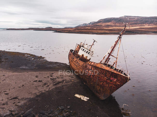 Deserted ship near stony coast — Stock Photo