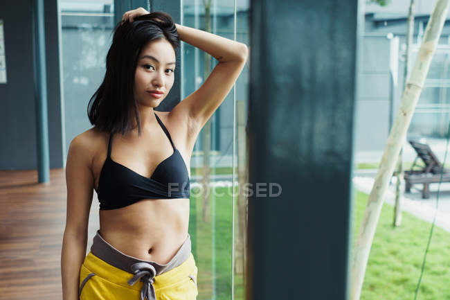 Jolie asiatique femme dans sportswear toucher cheveux et regarder caméra — Photo de stock