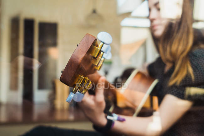 Mulher tocando guitarra atrás da janela em casa — Fotografia de Stock