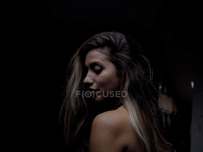 Sensual woman in darkness looking down — Stock Photo