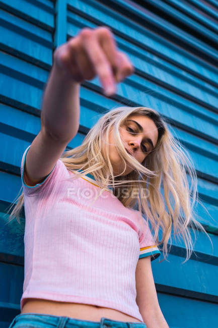 Femme penchée sur le mur bleu sur la rue et montrant le majeur — Photo de stock
