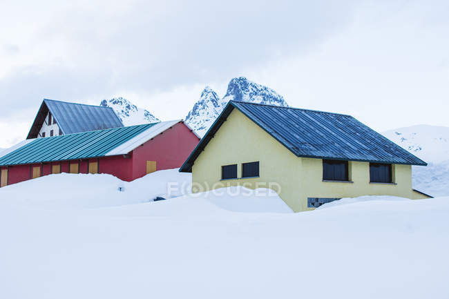 Pequeñas casas coloridas y picos nevados blancos en invierno, Valle De Tena, España - foto de stock