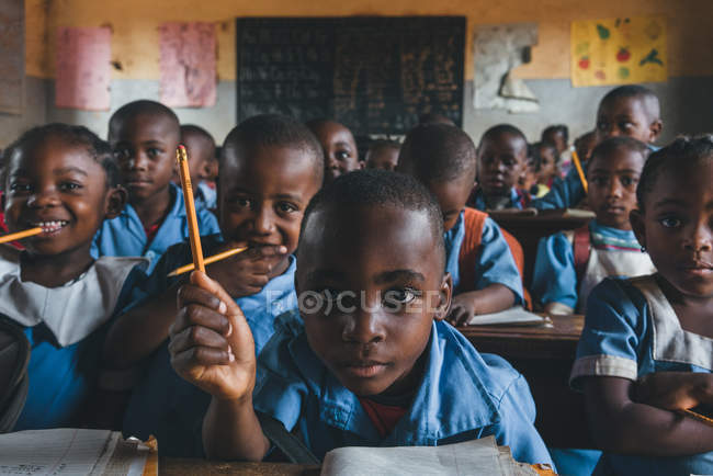 Камерун - Африка - 5 квітня 2018: Африканські учнів сидить з олівцями в класі і, дивлячись на камеру — стокове фото