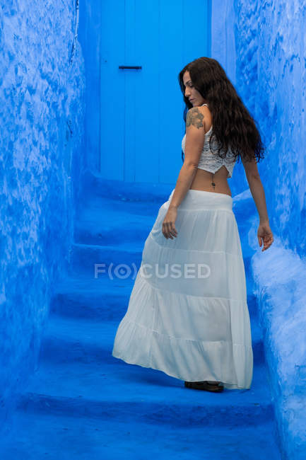 Rear view of woman walking on blue stairs — Stock Photo