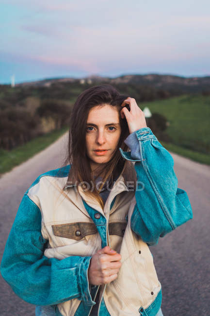 Retrato de Jovem mulher de pé na estrada no campo — Fotografia de Stock