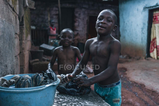 Kamerun - Afrika - 5. April 2018: Afrikanische Jungen stehen auf der Straße und waschen Kleidung — Stockfoto
