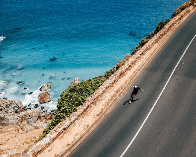 De dessus skateboarder homme chevauchant sur la route asphaltée sur la colline dans la journée ensoleillée. — Photo de stock