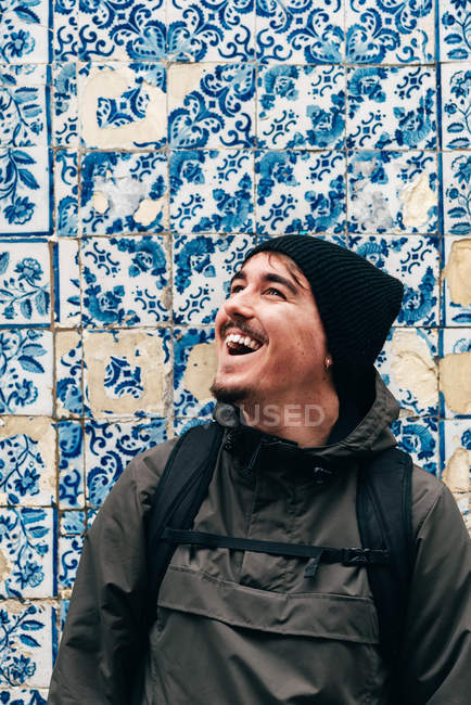 Cheerful tourist man standing at wall with blue tiles — Stock Photo