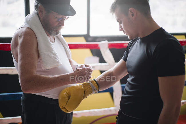 Side view of adult man with cigar training boxer in the gym. — Stock Photo