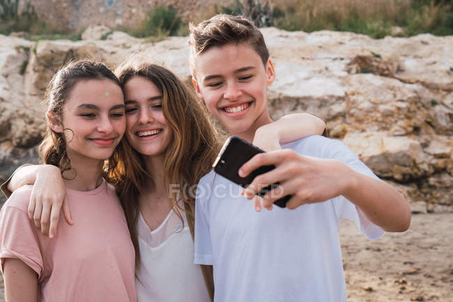 Sorridente adolescenti prendendo selfie in riva al mare — Foto stock