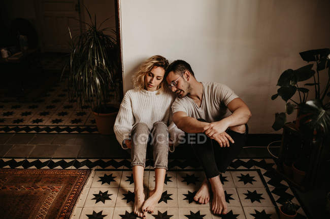 Romántico hombre y mujer sentado en el suelo en casa juntos - foto de stock