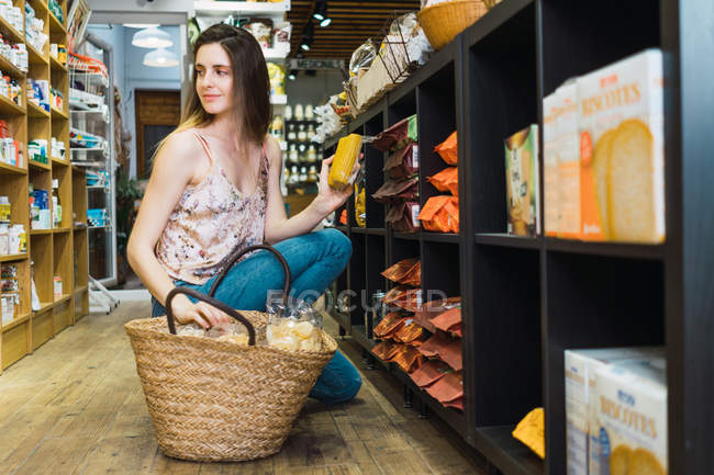 Женщина собирает продукты в корзине в супермаркете — стоковое фото