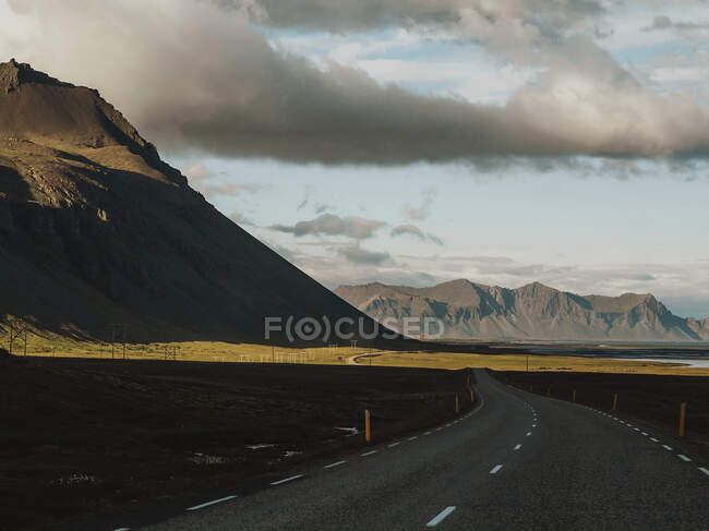Vista panorámica al camino vacío en verdes montañas pintorescas en día nublado. - foto de stock