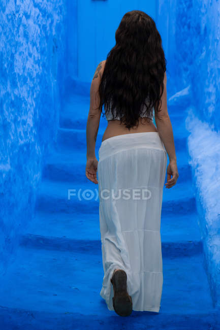 Visão traseira da mulher andando em escadas azuis — Fotografia de Stock