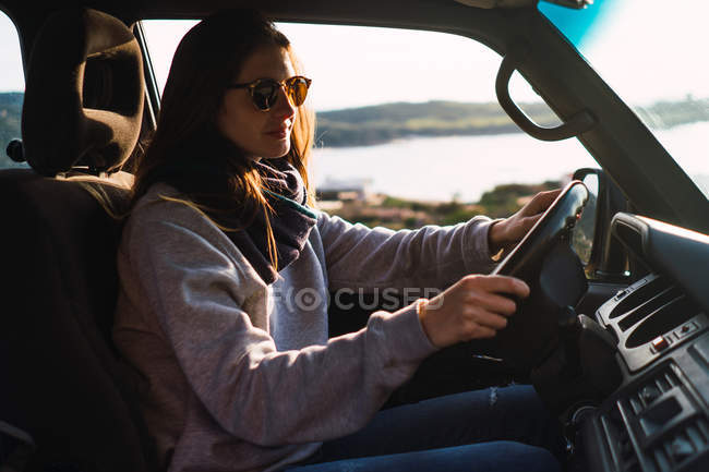 Junge Frau mit Sonnenbrille fährt Auto in der Natur — Stockfoto