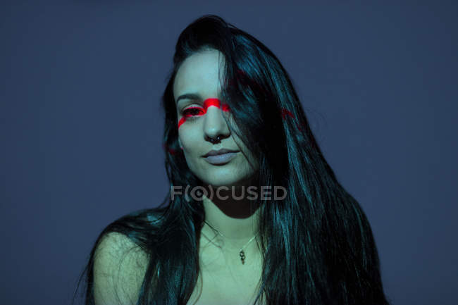 Junge attraktive Frau mit rotem Strich im Gesicht, die in die Kamera schaut — Stockfoto