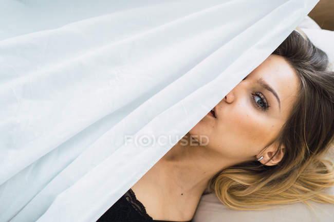 Portrait of Alluring girl in black bra covering with blanket — Stock Photo