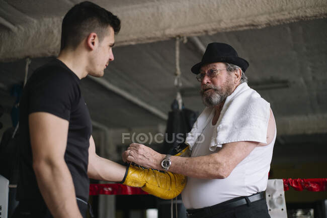 Side view of adult trainer interacting and helping to sportsman in the gym. — Stock Photo
