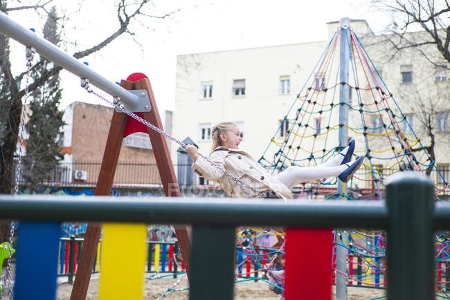 Souriant fille blonde balançant dans le parc — Photo de stock