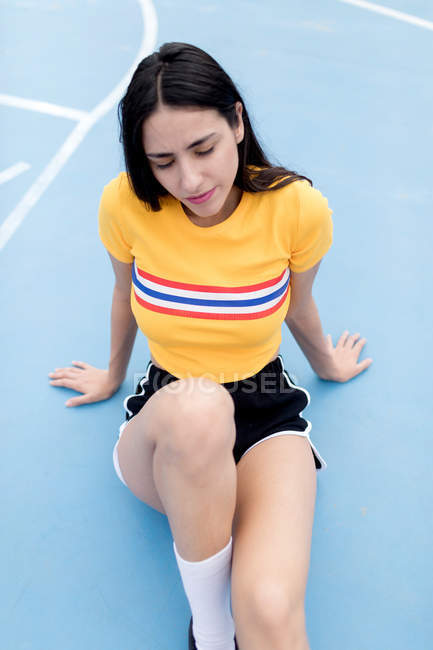 Jeune femme assise sur un terrain de sport — Photo de stock