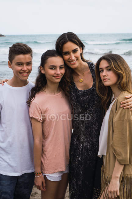 Portrait of woman and teenagers hugging together on seashore — Stock Photo