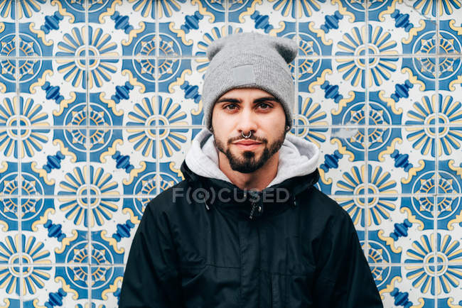 Retrato de turista masculino reflexivo de pie en la pared con azulejos azules - foto de stock