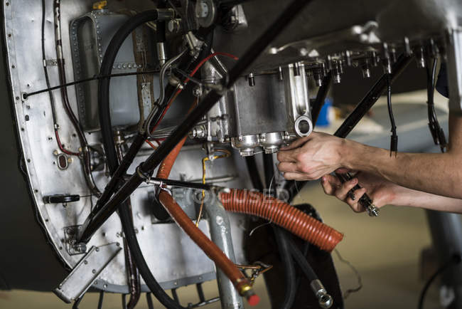 Hands of aircraft mechanic fixing engine of small airplane in hangar — Stock Photo
