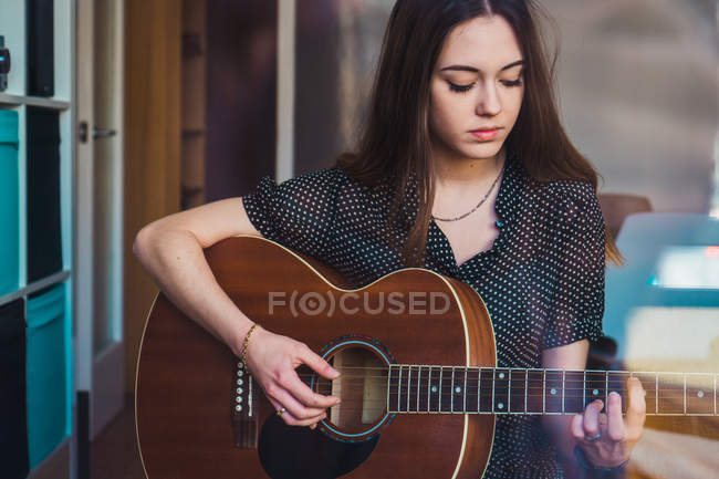 Задумлива молода жінка грає на гітарі — стокове фото