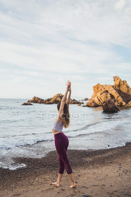 Forme jeune femme étirant au bord de la mer — Photo de stock