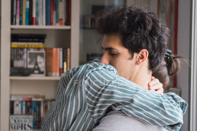 Молодий чоловік і жінка в піжамі, обіймаючись закритими очима вдома — стокове фото