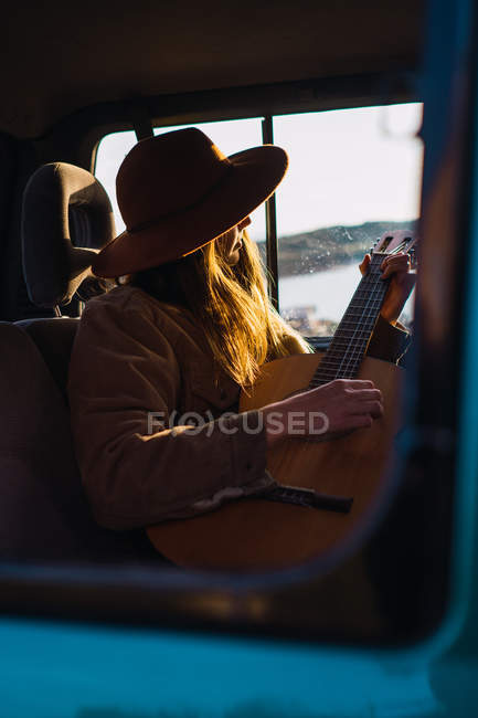 Woman with guitar sitting in car in nature — Stock Photo