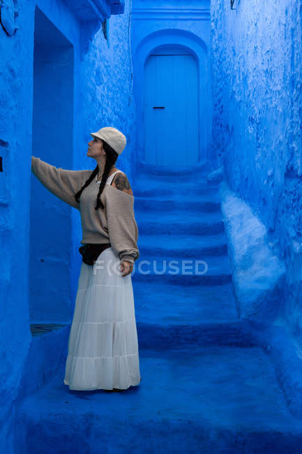 Woman touching blue dyed wall on street in Morocco — Stock Photo