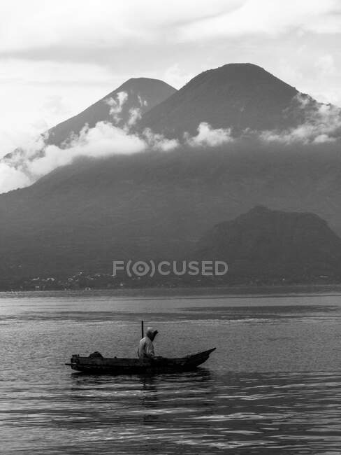 Uomo che naviga sul lago con le montagne — Foto stock