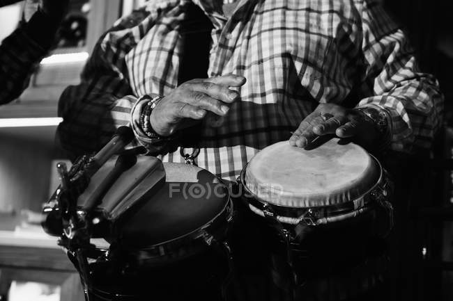 Обрезанный музыкант, играющий на барабанах в ночном клубе, черно-белый кадр с длительной экспозицией — стоковое фото