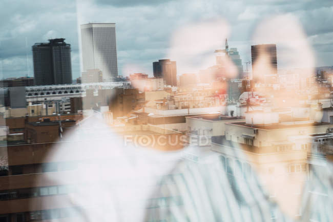 Dreamy couple standing at window with city reflection on background — Stock Photo