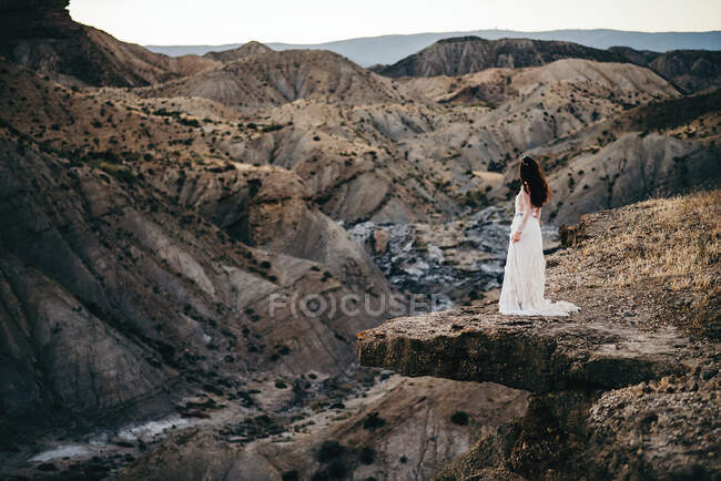 Вид сбоку на молодую женщину в платье и взгляд вдаль в горах. — стоковое фото
