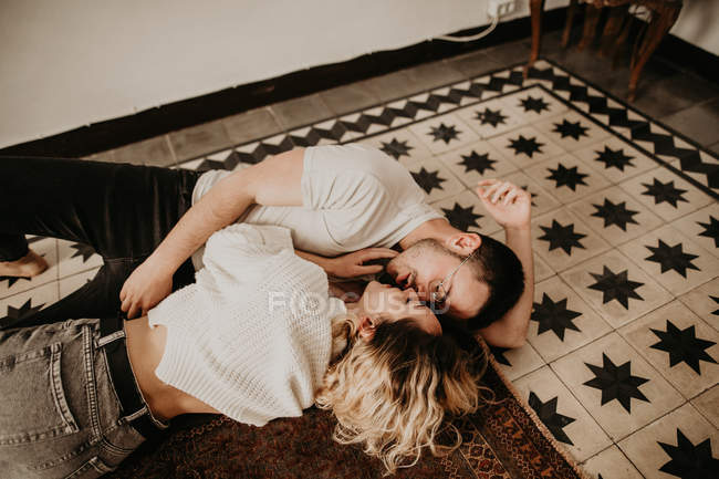 Homem e mulher romântico feliz deitado no chão e beijando em casa — Fotografia de Stock