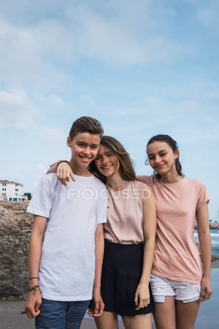 Portrait of smiling teenagers standing on seashore in summer — Stock Photo