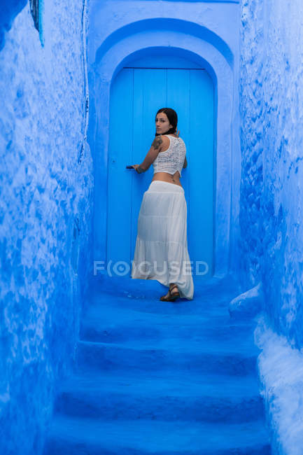 Mujer abriendo puerta azul en la calle, Marruecos - foto de stock
