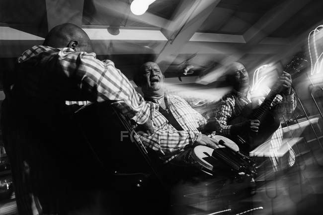 Кубинское музыкальное трио, действующее в ночном клубе, черно-белый кадр с длительной экспозицией — стоковое фото