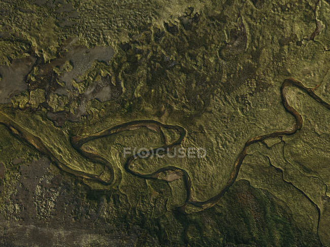 Сверху течет маленькая река в зеленом поле. — стоковое фото