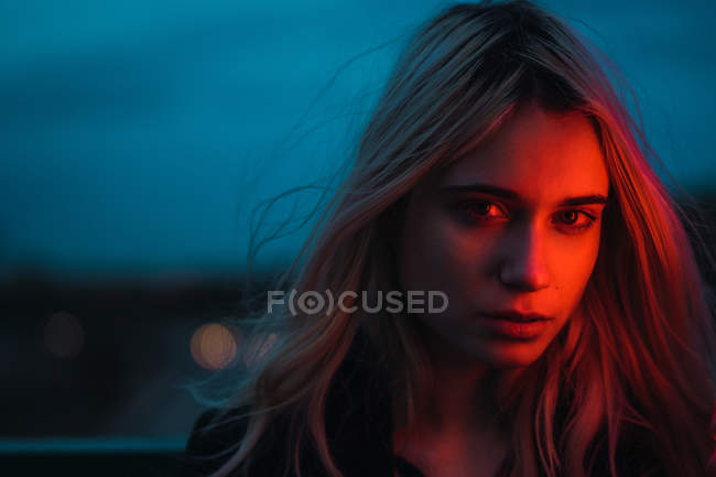 Femme blonde réfléchie regardant la caméra au crépuscule — Photo de stock