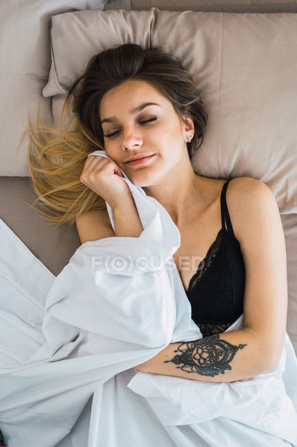 Усміхнена молода жінка з закритими очима в бюстгальтері, що покриває ковдрою — стокове фото