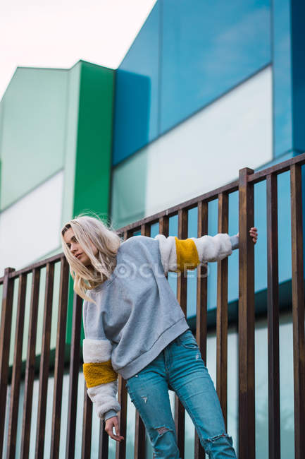 Mulher bonita apoiando-se em cerca contra casas coloridas modernas — Fotografia de Stock